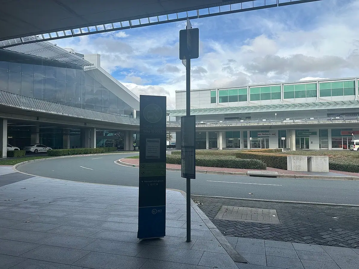 A bus stop sign outside a modern airport terminal building
